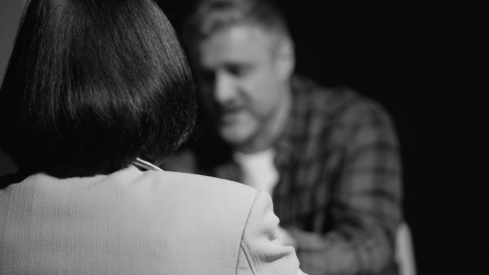 Woman seen from behind facing a blurred man across a table in a black-and-white scene - ev law in Bundall, QLD