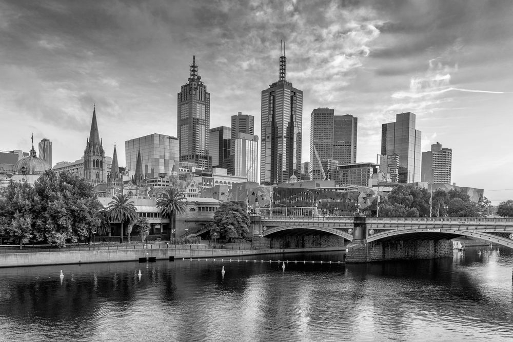 Sunlit city skyline with cathedral spires, tall modern towers, river, and a bridge at sunset - ev law in Bundall, QLD