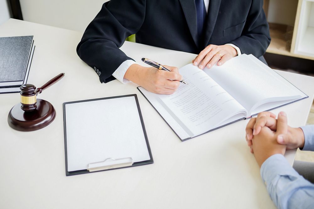 Lawyer signing documents at a desk during a consultation, with a gavel and clipboard nearby - ev law in Bundall, QLD