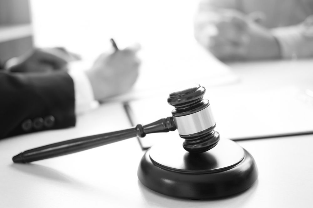 Judge's gavel on base beside a hand writing in a blurred office scene - ev law in Bundall, QLD