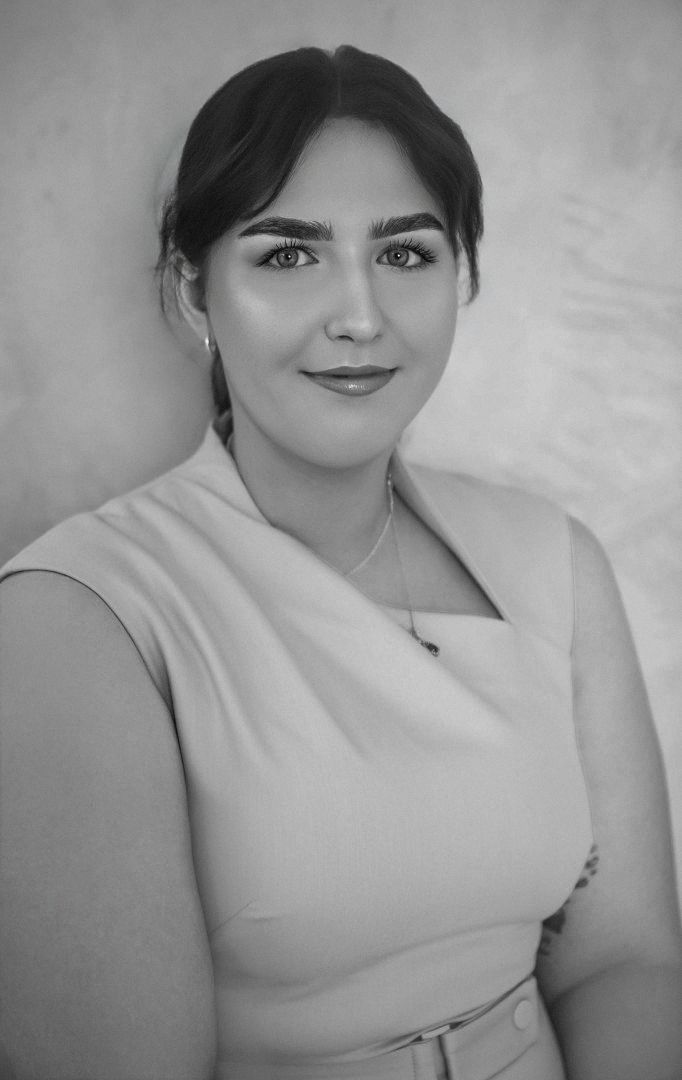 Studio portrait of a person in a light dress, seated and smiling against a soft gray background - ev law in Bundall, QLD
