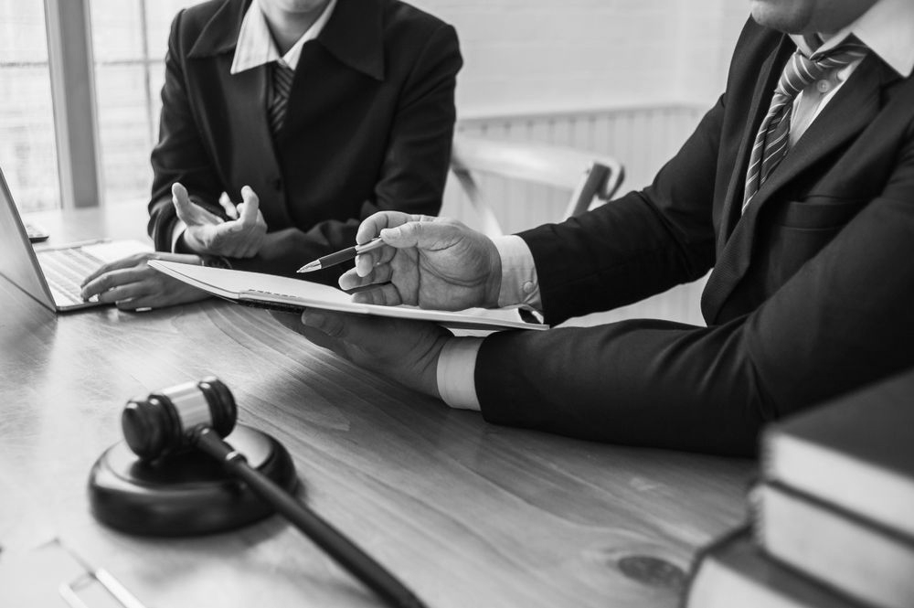 Two businesspeople in suits reviewing documents at a conference table with a gavel and books nearby - ev law in Bundall, QLD