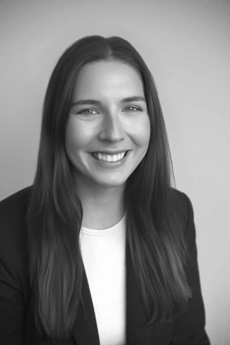 Smiling woman in a dark blazer and white top against a plain gray background - ev law in Bundall, QLD