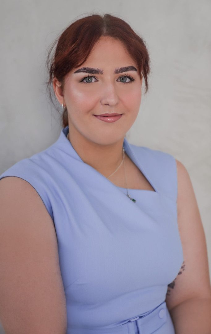 Portrait of a smiling person in a light blue sleeveless dress against a gray background - ev law in Bundall, QLD
