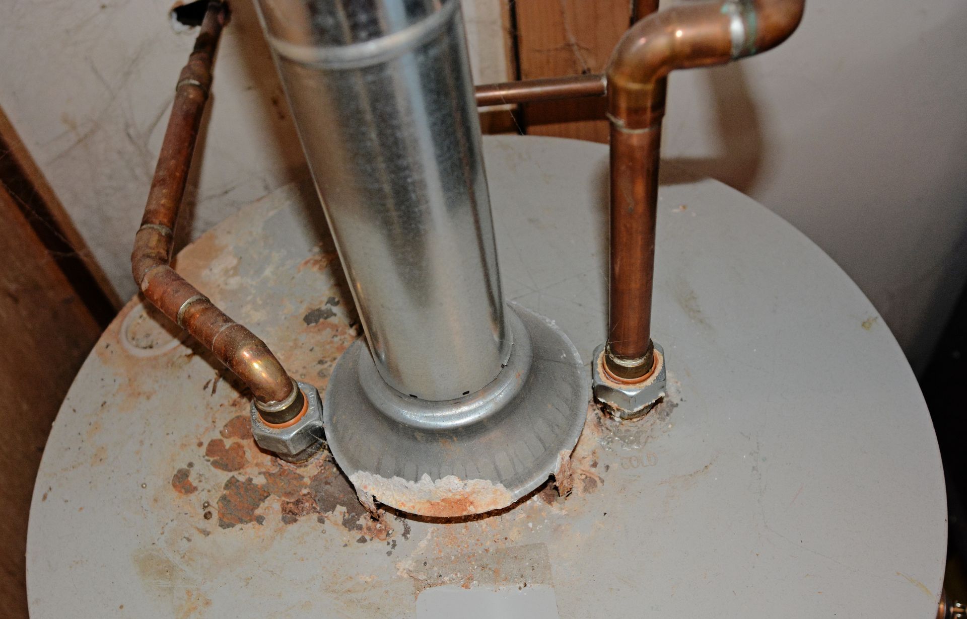 A plumber in uniform working on a water meter and pipes inside a cabinet. A plumber in uniform working on a water meter and pipes inside a cabinet.
