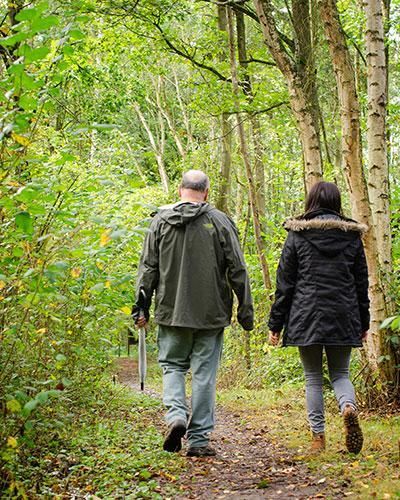 Medewerker en coach wandelen door het bos tijdens een traject voor werkstress, loopbaanvragen en het hervinden van richting.