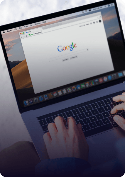 Person using a laptop with Google search open, typing on the keyboard.