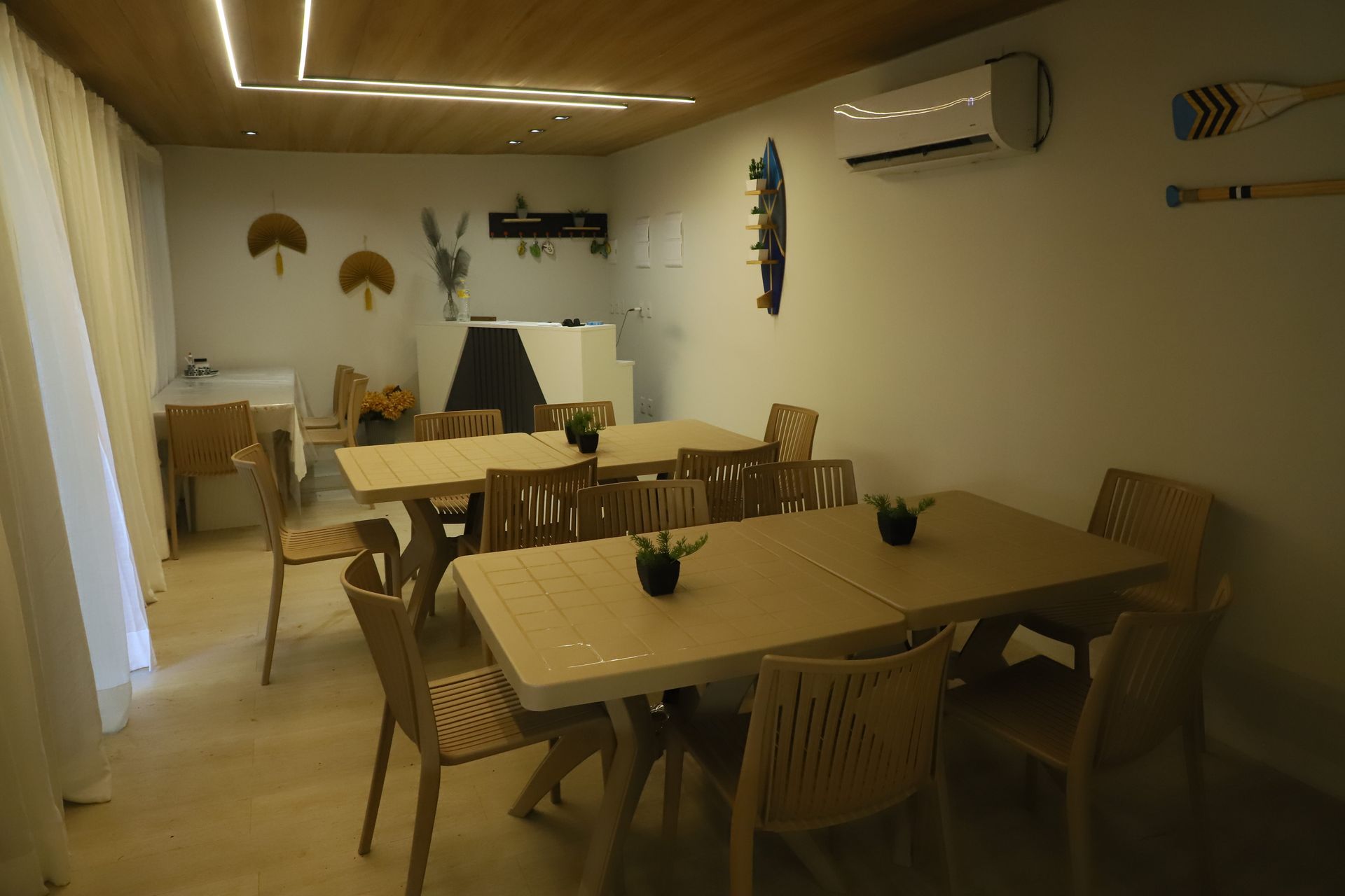Sala de jantar moderna com mesas e cadeiras de madeira, decoração de parede e iluminação aconchegante.