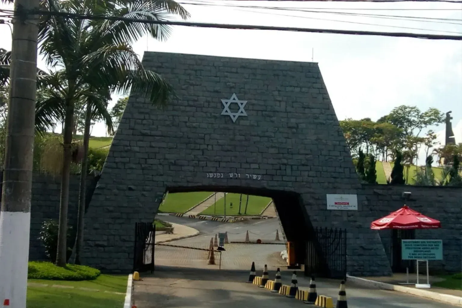 Portal de pedra com a Estrela de Davi acima da entrada de um complexo, visto da estrada.