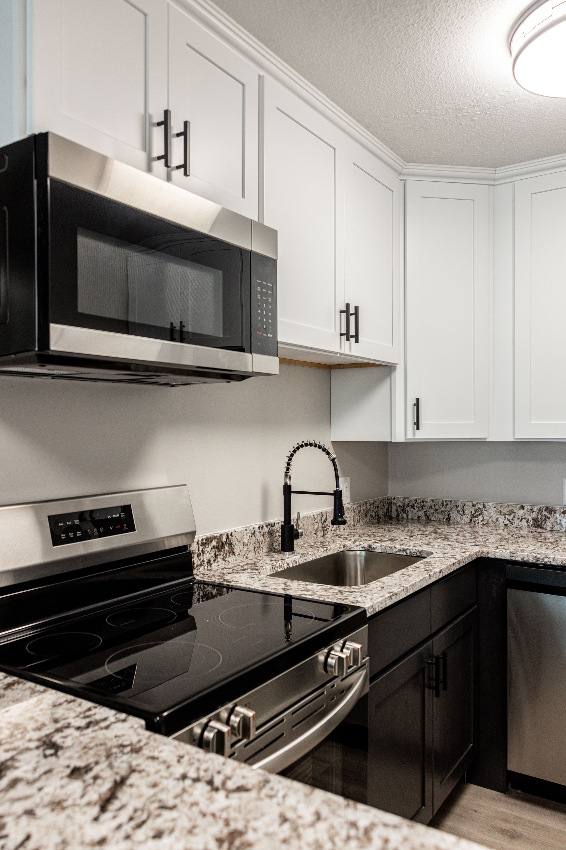 Modern white kitchen with black appliances and granite countertops