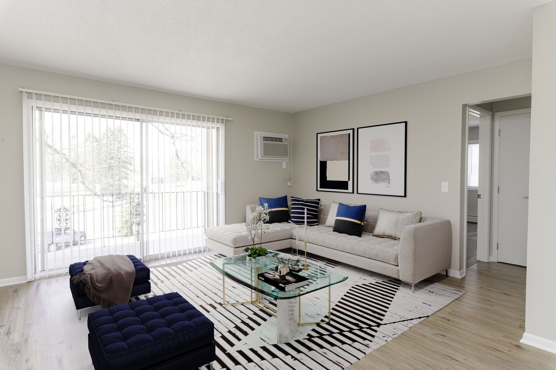 Bright living room with beige sofa, blue chair, glass coffee table, and large window with sheer curtains