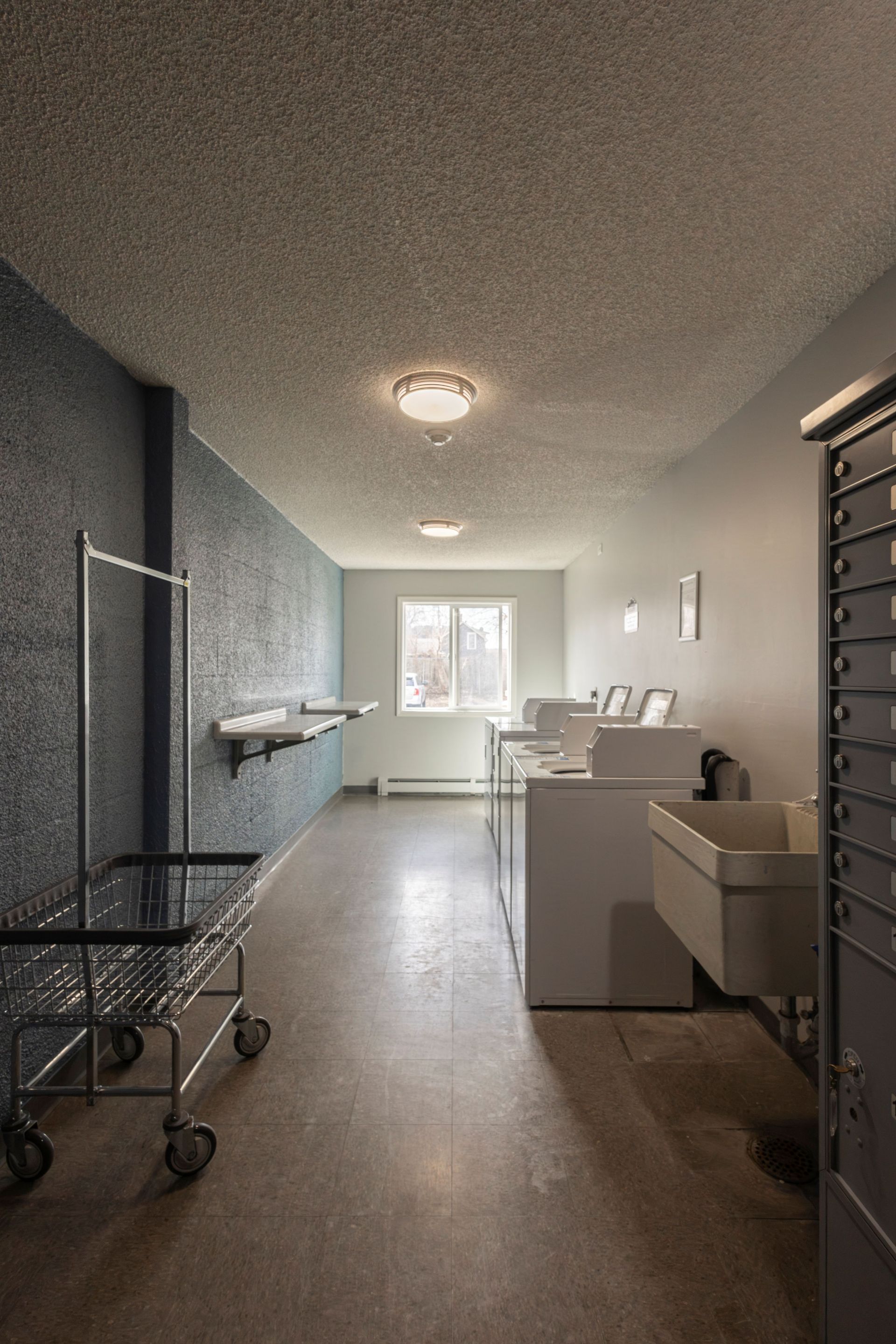 Bright hallway in a clinic or lab with carts, counters, and a window at the end.
