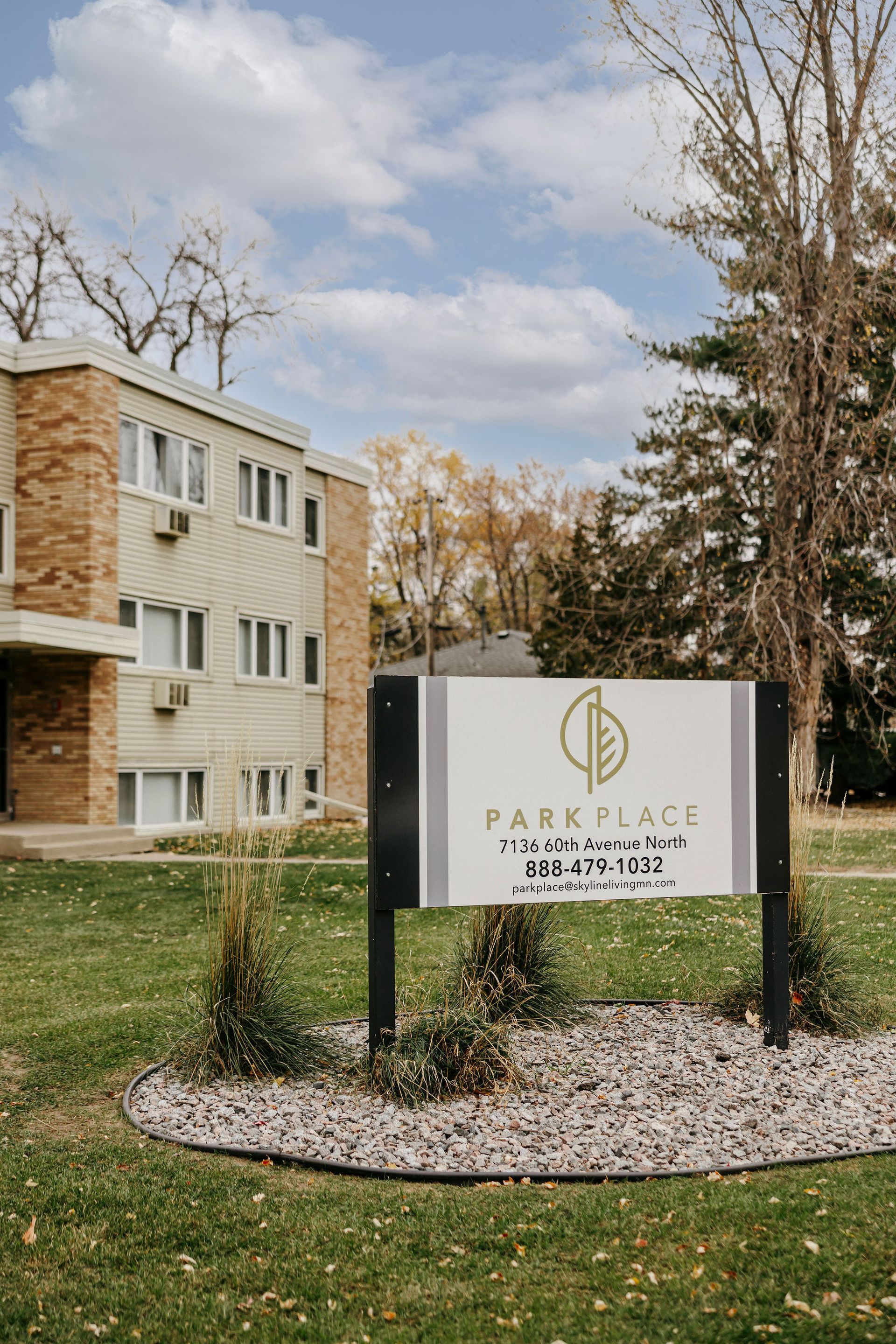 Apartment building with a Park Place sign in front, surrounded by grass and trees