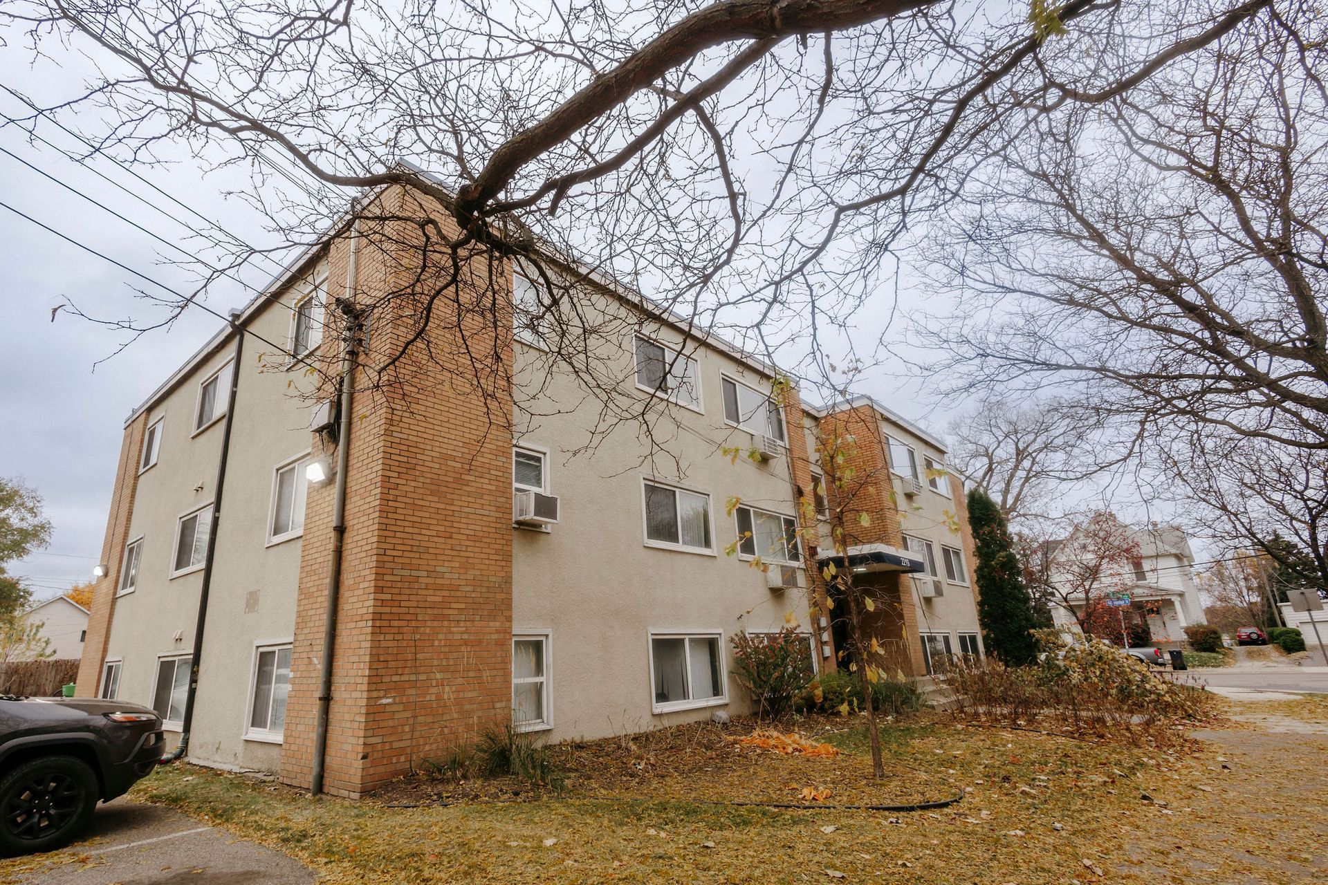 Three-story brick apartment building under bare trees on an autumn street