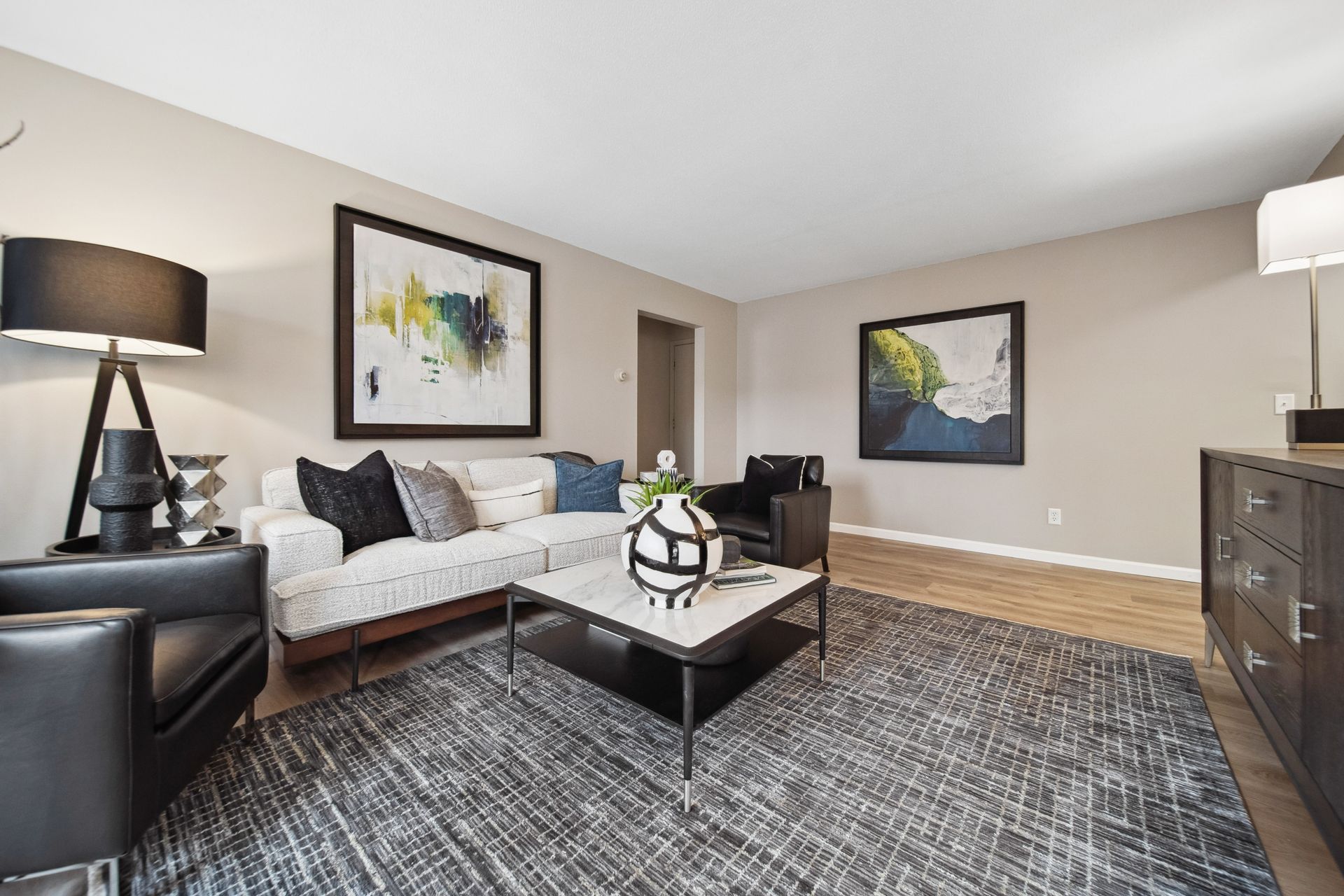 Modern living room with white sofa, black accents, patterned rug, and wall art
