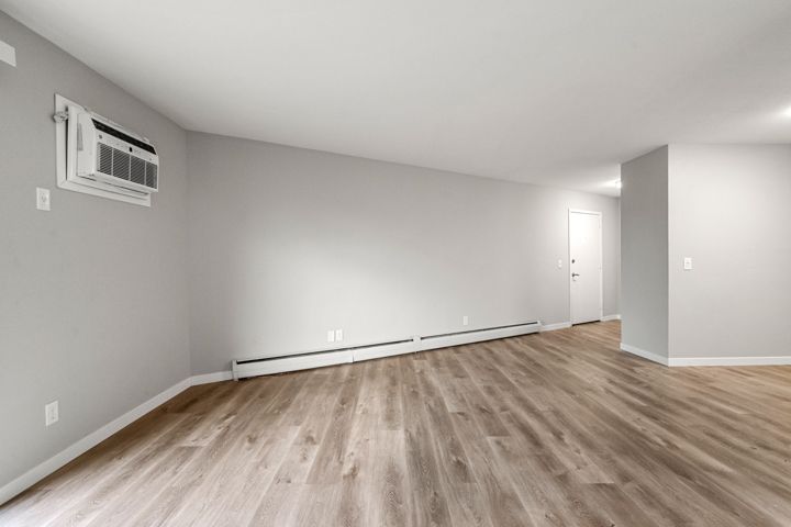 empty apartment living room with wall unit AC - Skyline Real Estate Services