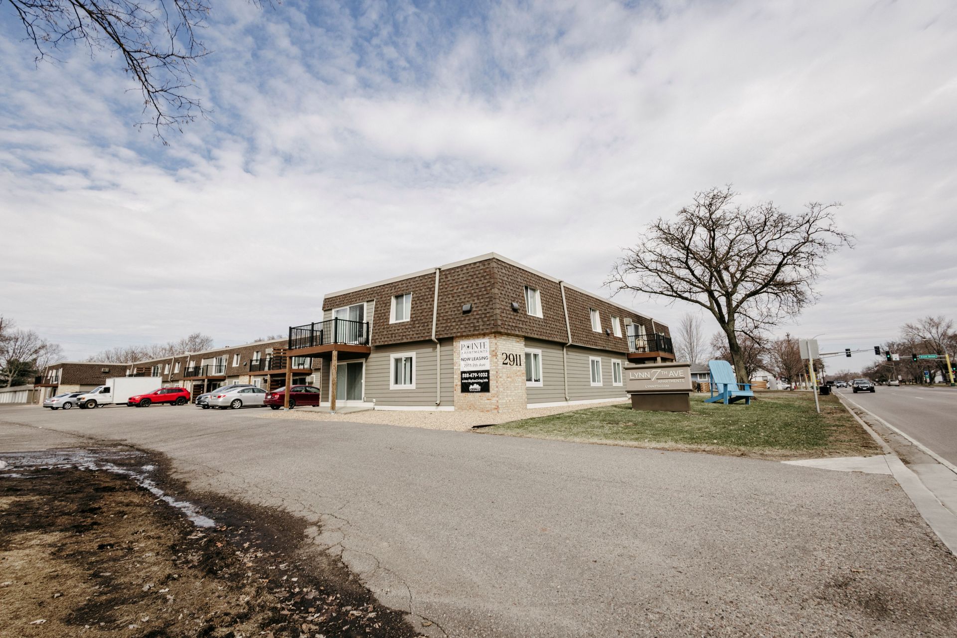 Corner building with brown roof beside a wide gravel lot under a cloudy sky