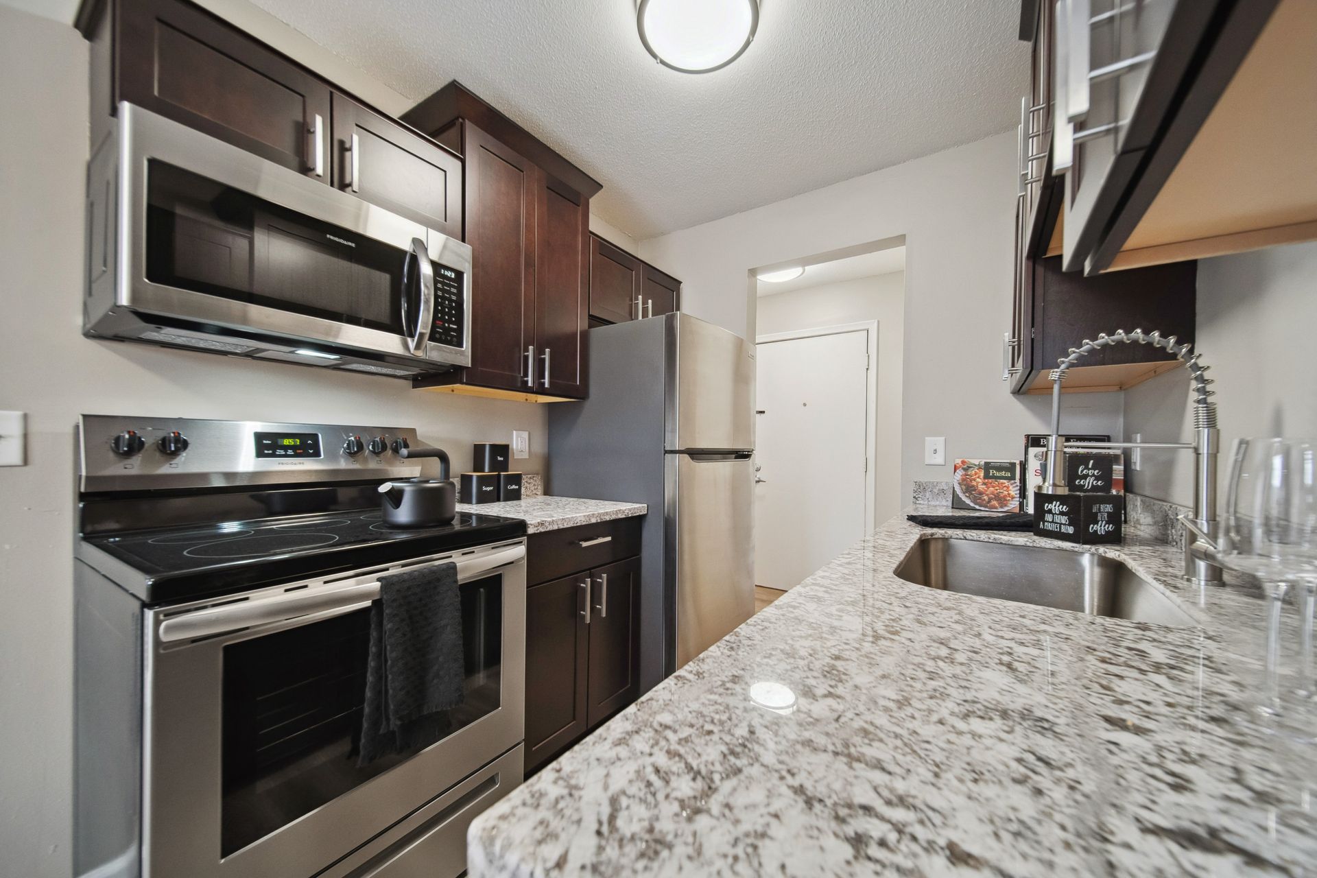 Modern kitchen with stainless steel appliances, dark cabinets, and a granite countertop