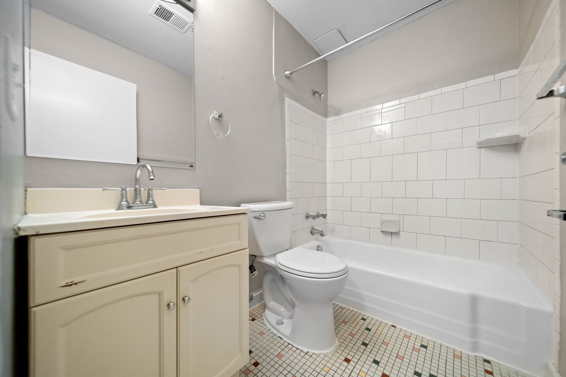 Bright white bathroom with vanity, toilet, and bathtub with white tile surround
