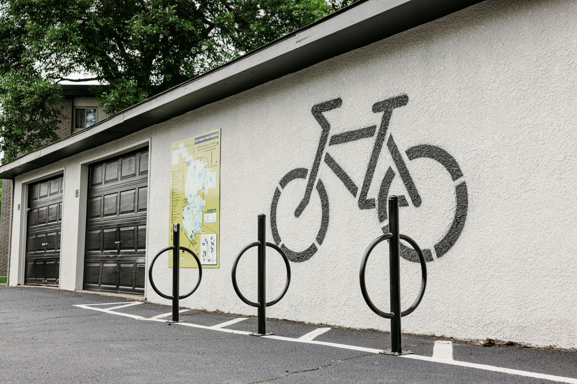 Bike mural on a white wall beside parked bicycle racks and a garage door