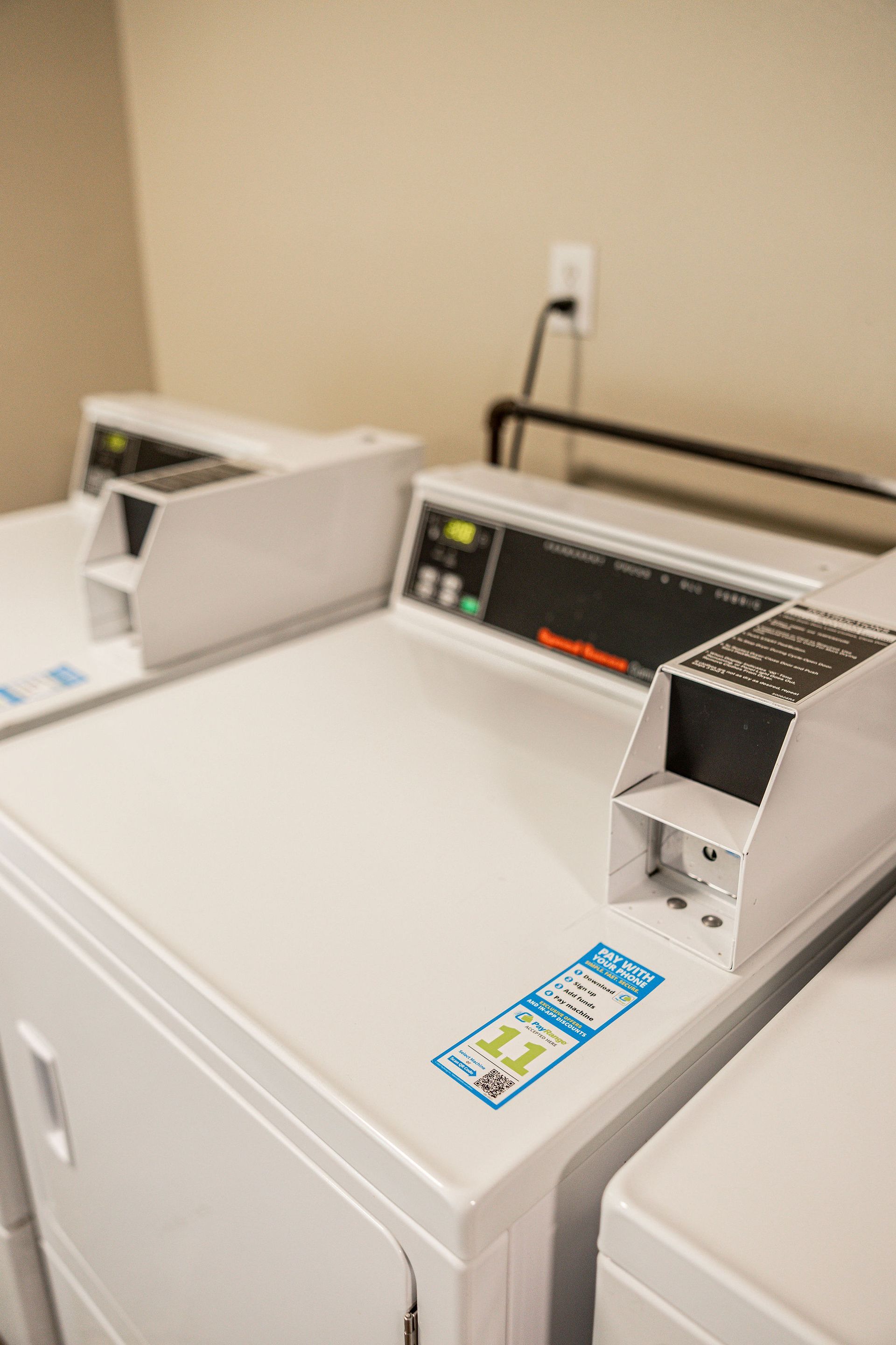 Laundry machines with coin slots and control panels in a utility room