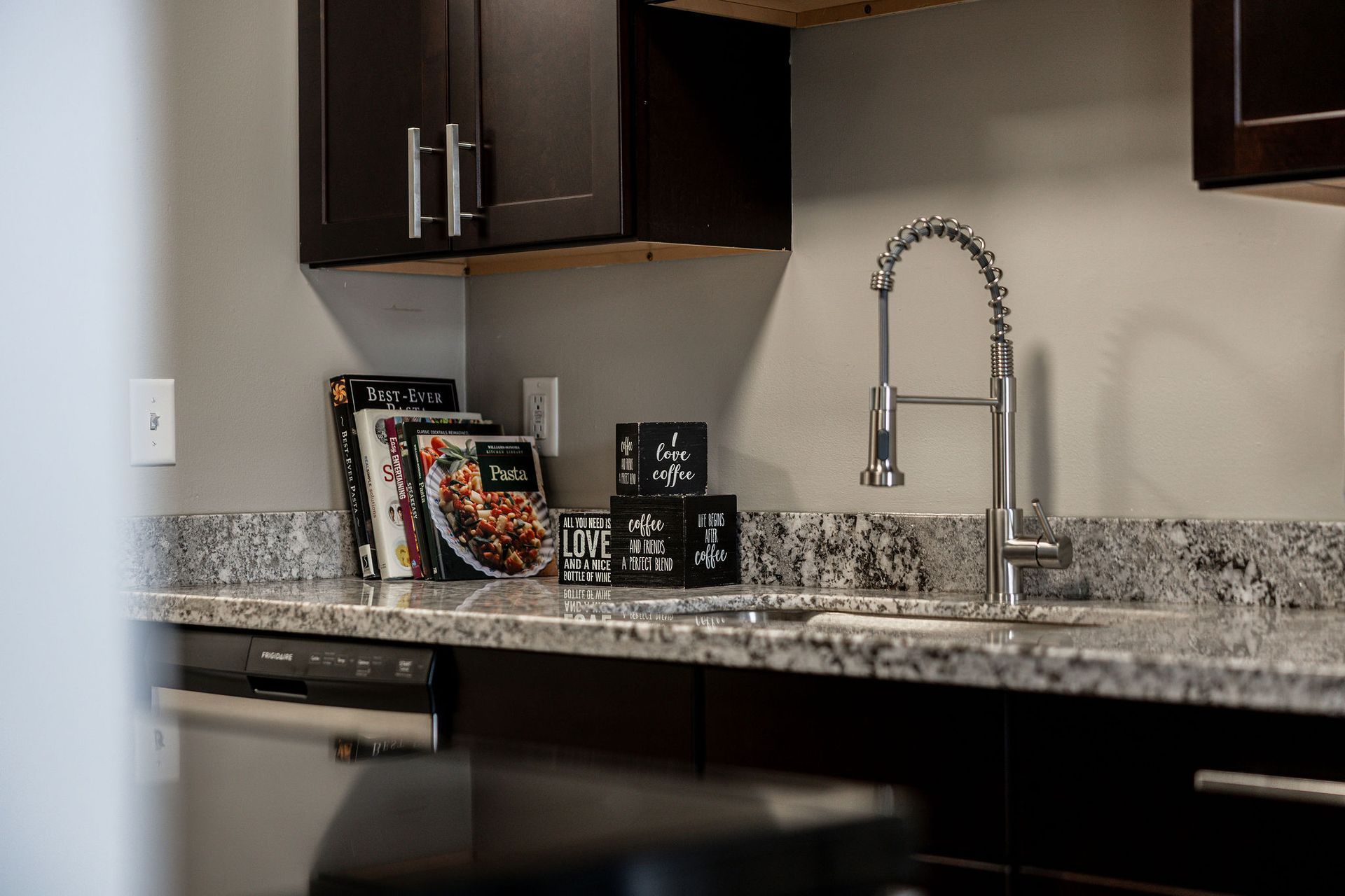 Modern kitchen with dark cabinets, granite countertop, and stainless faucet.