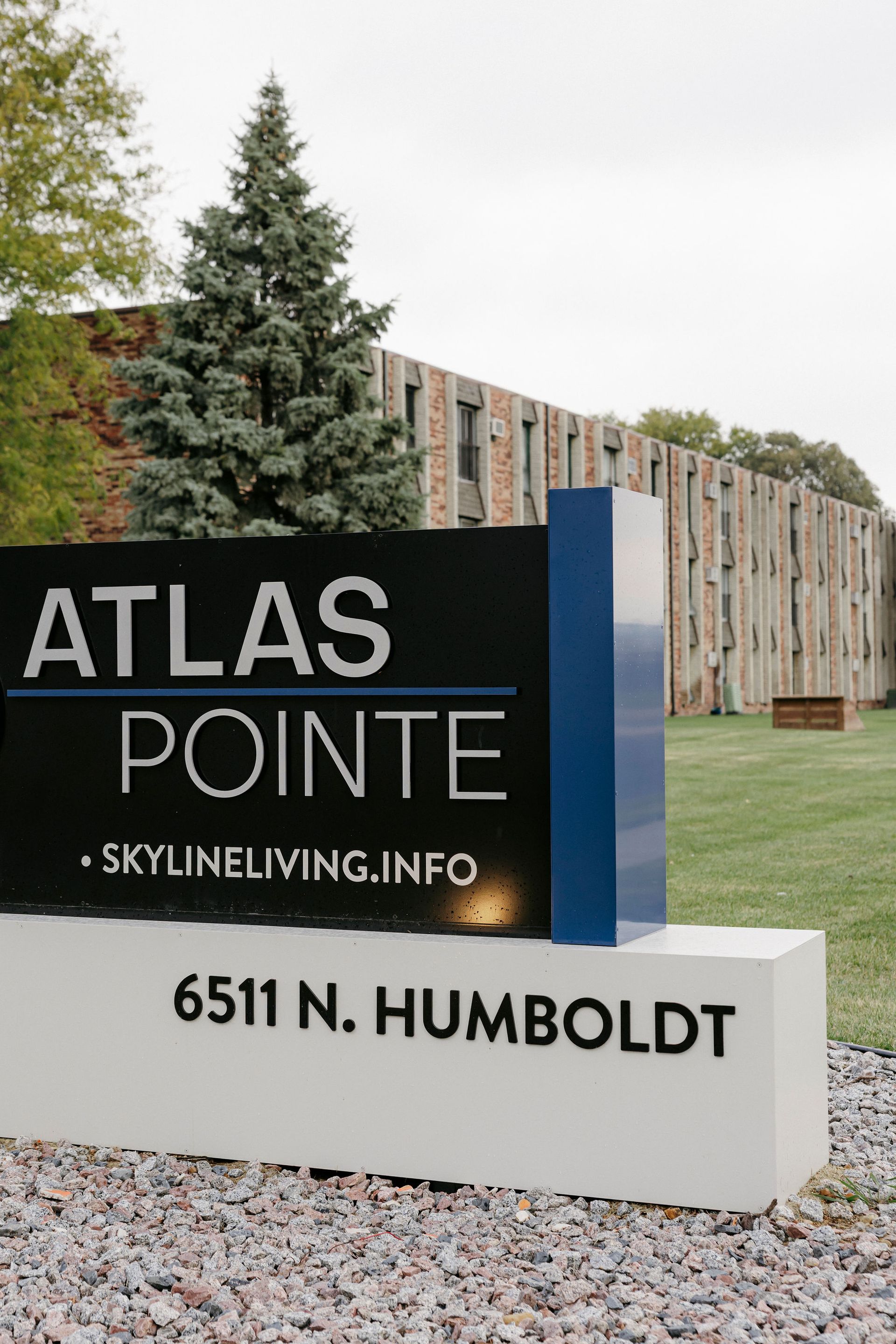 Atlas Pointe apartment sign with address 6511 N. Humboldt, in front of a building and trees.