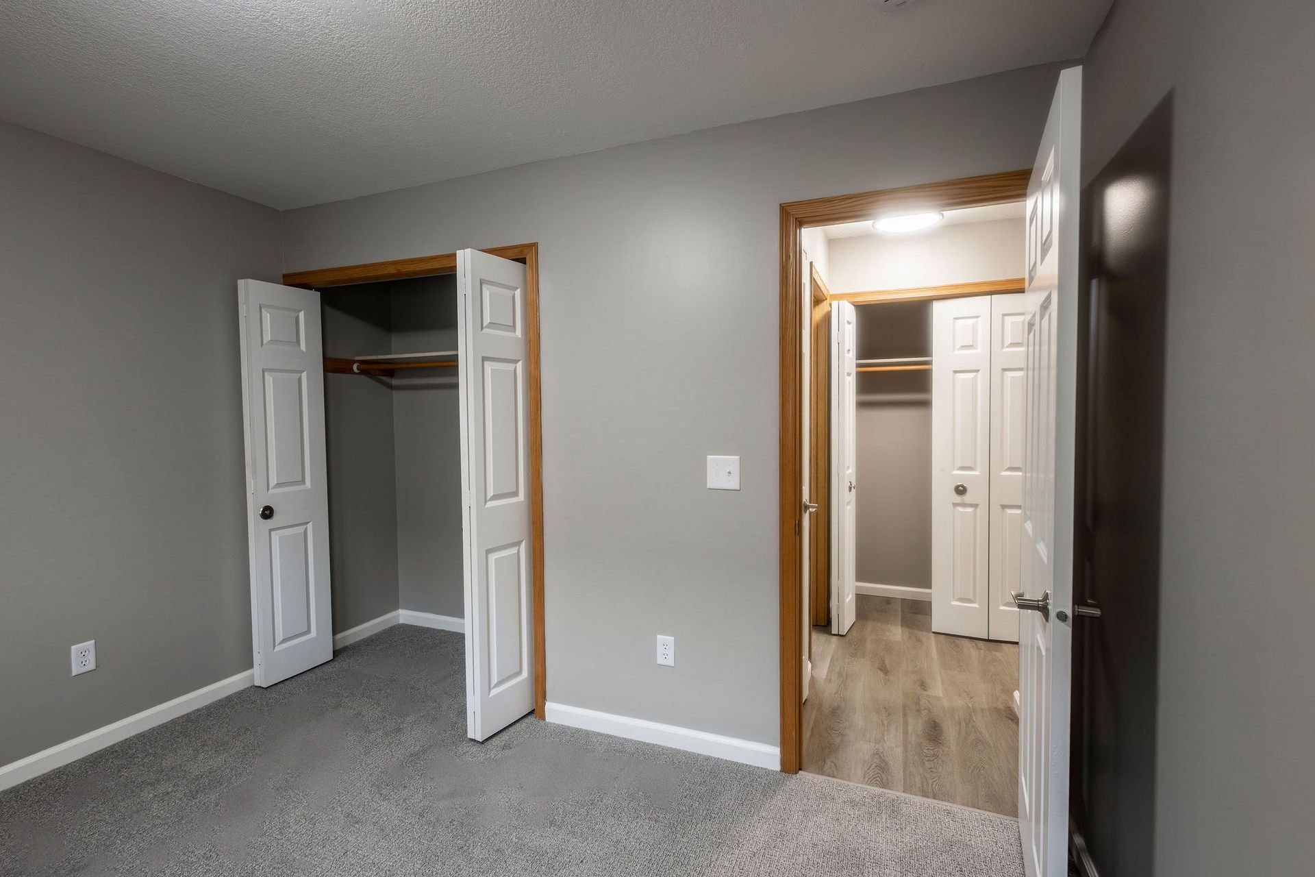 Empty gray bedroom with open closet and doorway to a hall or bathroom