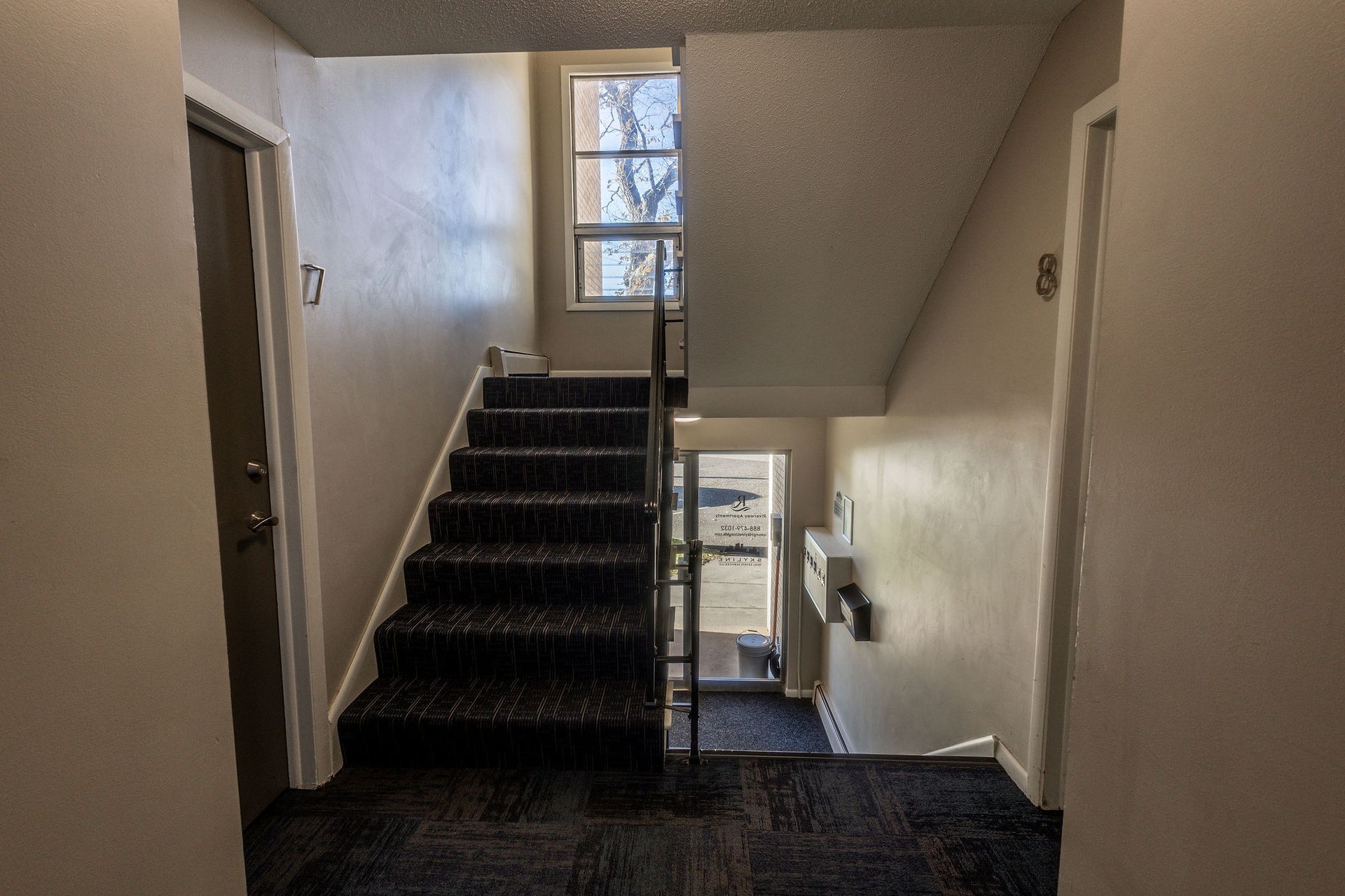 Interior stairwell with carpeted stairs, white walls, and a window at the landing.