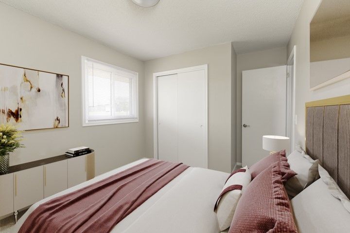 Bright bedroom with a bed, white walls, window, dresser, and closet doors