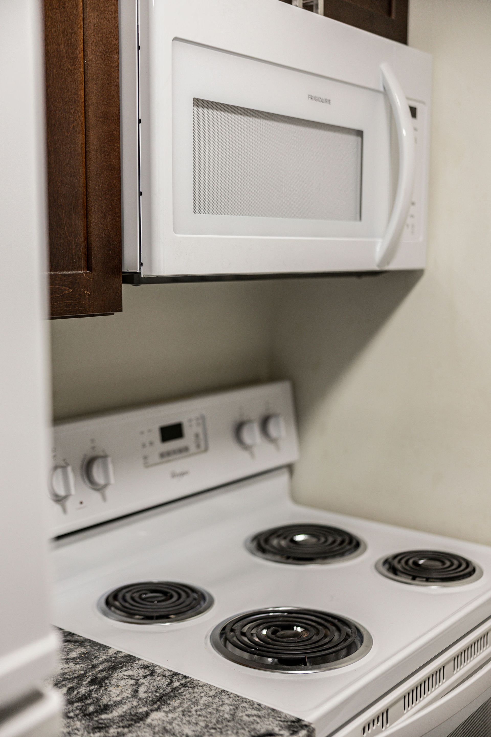 White stove and microwave in a small kitchen corner.