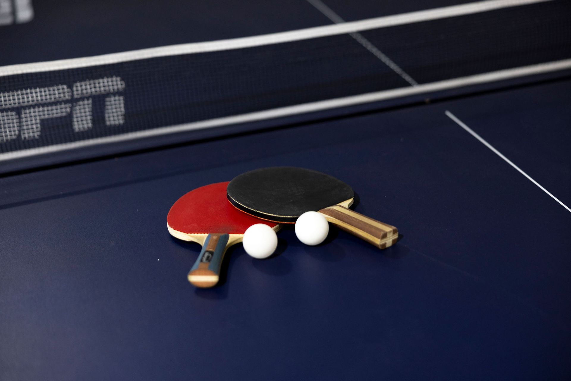 Two ping-pong paddles and two balls on a blue table tennis table