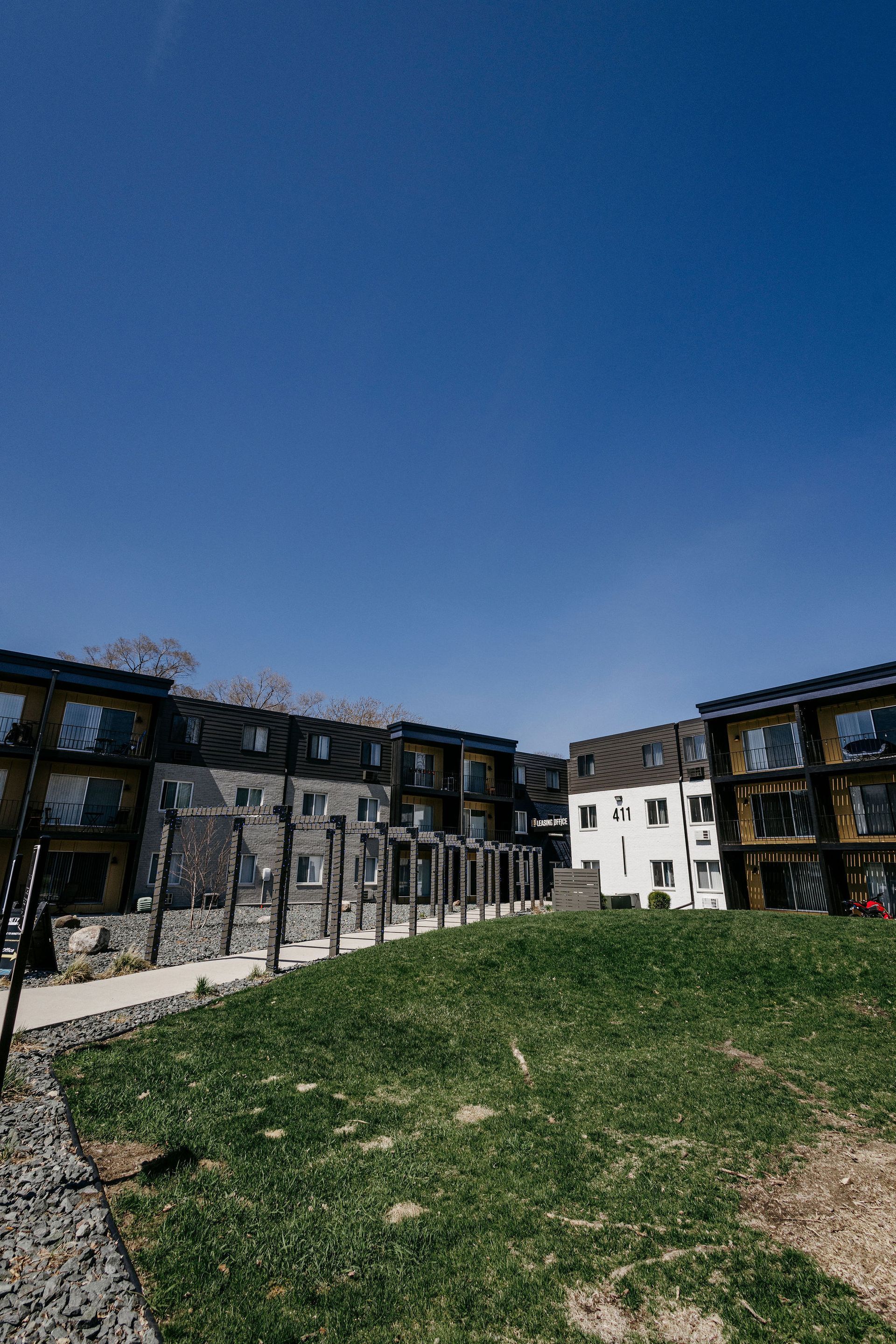 Apartment buildings around a grassy courtyard under a clear blue sky