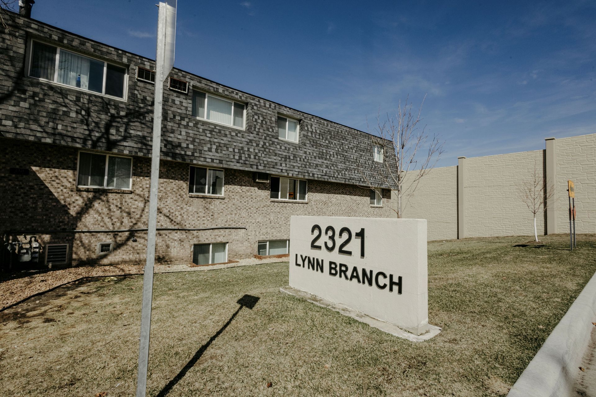 Sign for 2321 Lynn Branch outside a brick apartment building under a blue sky