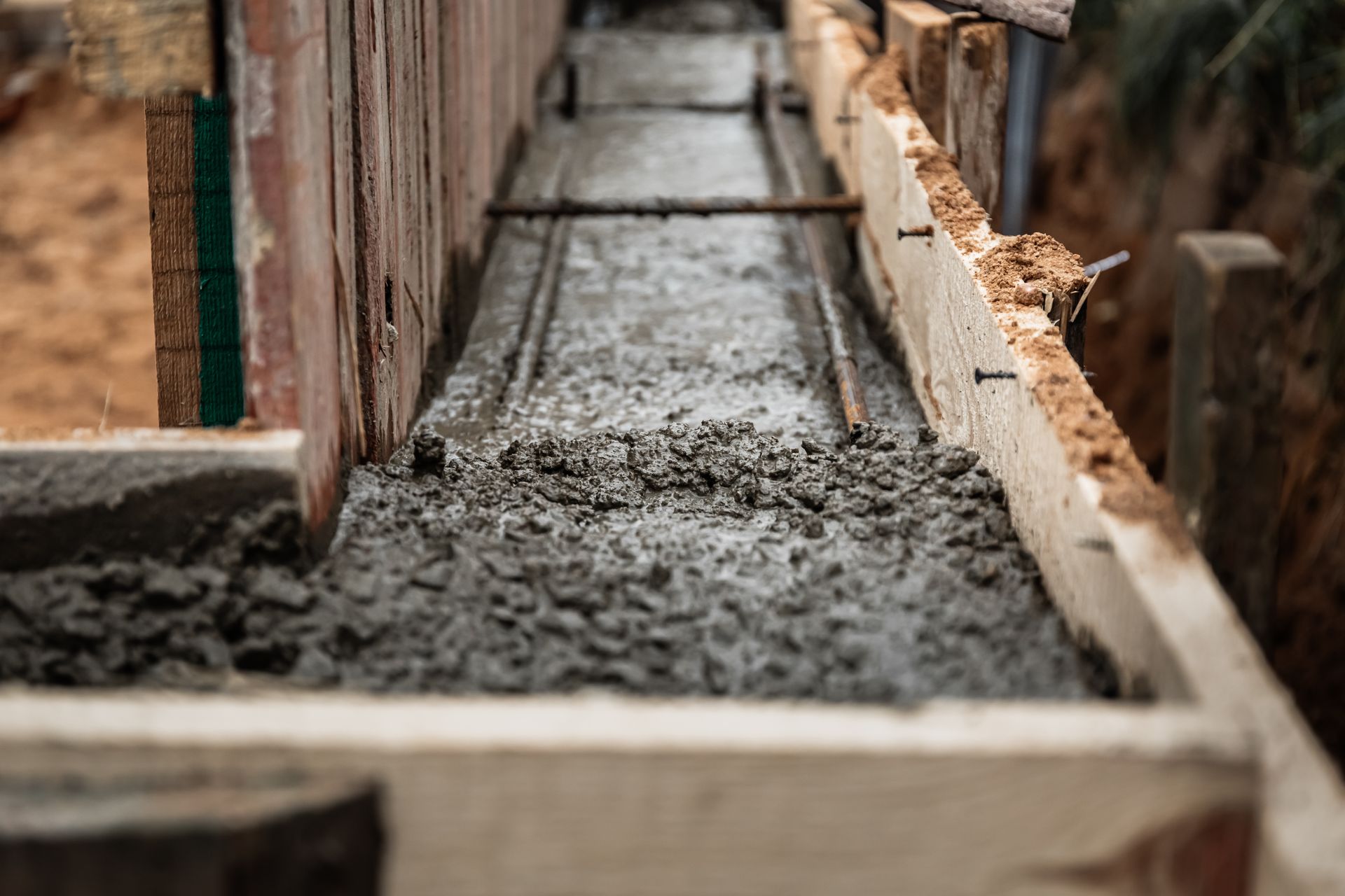 Fresh concrete poured into wooden forms, with rebar visible.
