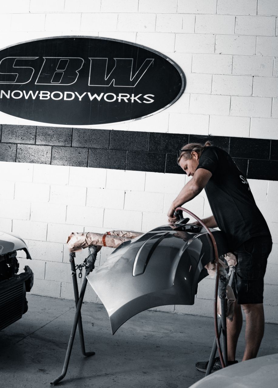 Side View Of A Man Polishing Car Bumper — Panel Beaters in Southport, QLD
