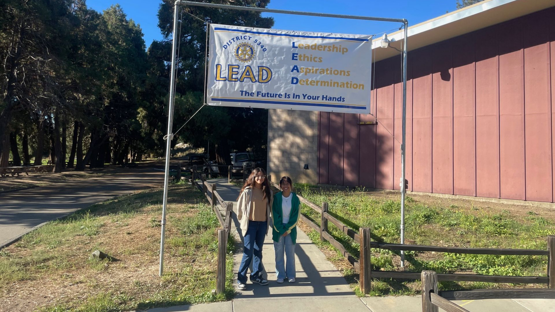 Two people stand under a banner labeled