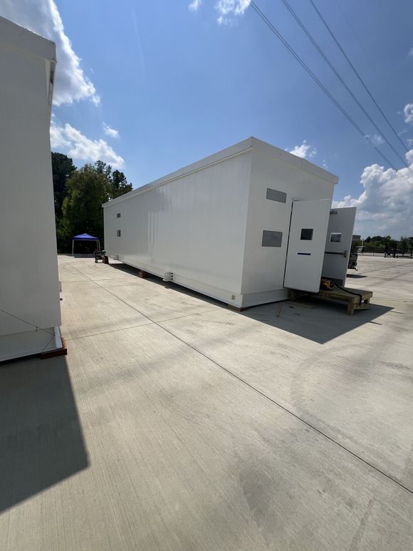 White rectangular building on a concrete surface under a sunny sky.