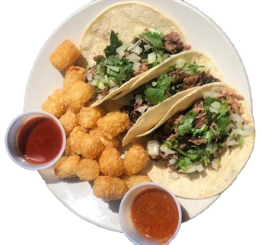 Tacos with cilantro and diced onions on a plate, with tortilla chips and two small salsa cups on a dark table