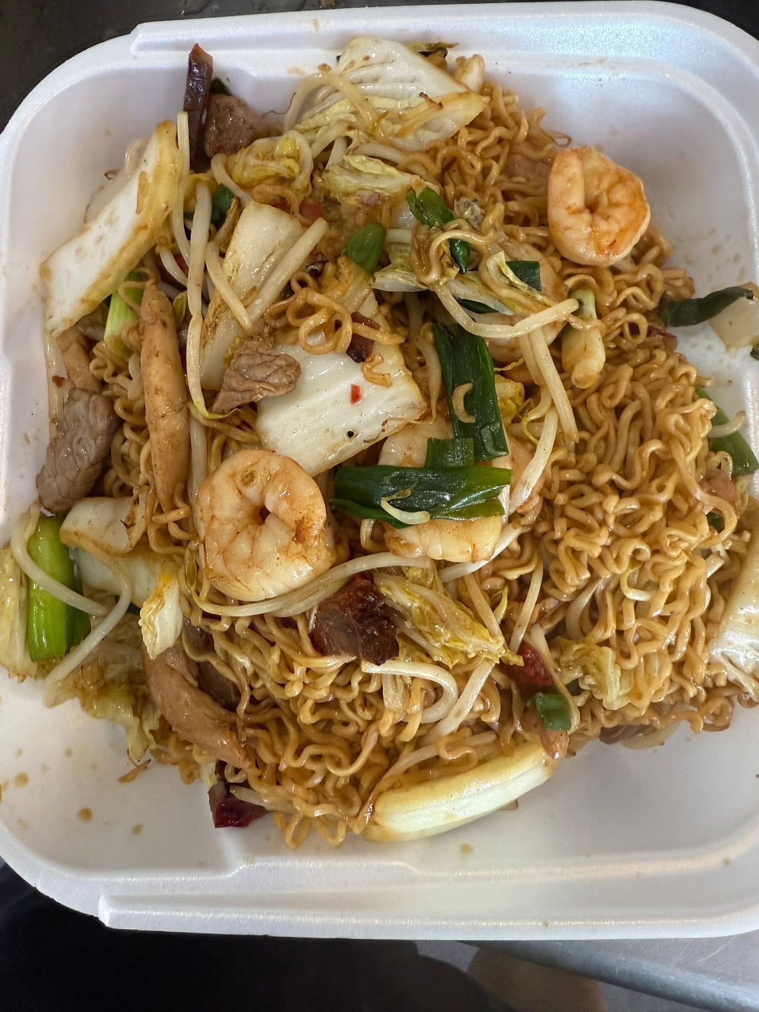 Takeout container of stir-fried noodles with shrimp, vegetables, and bean sprouts