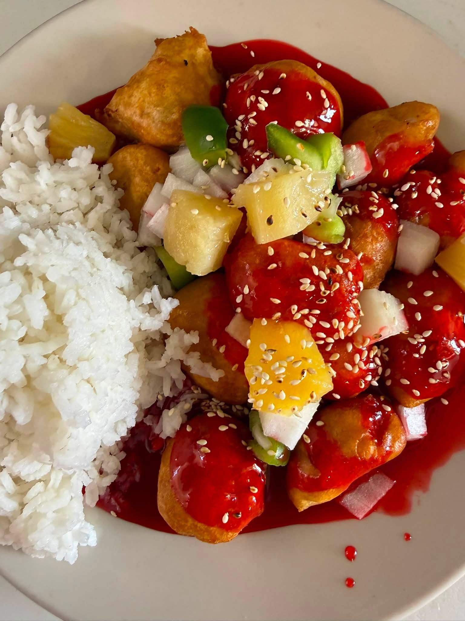 Plate of white rice and a colorful stir-fry with cherry tomatoes, pineapple, tofu, and sesame seeds
