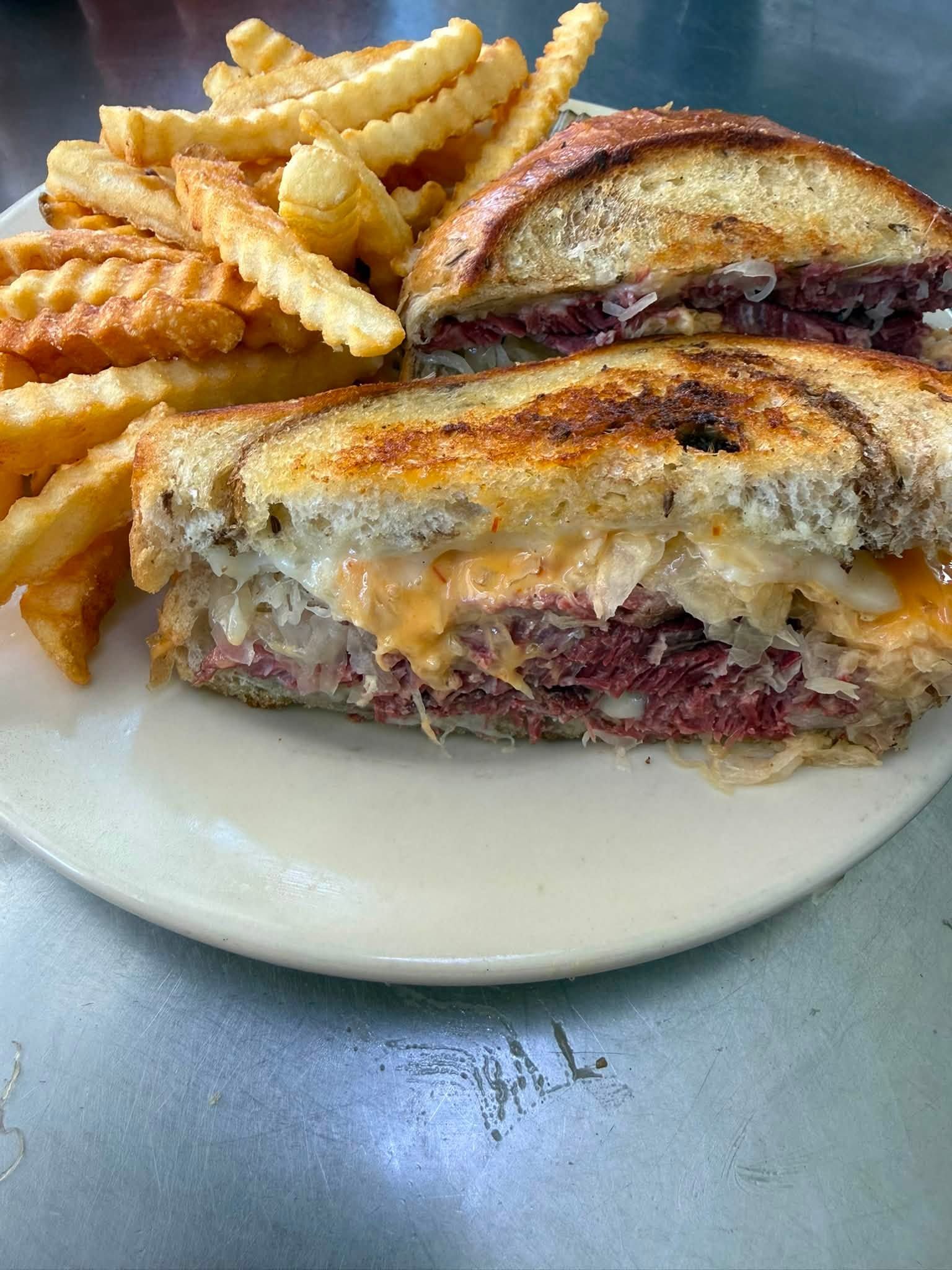 Grilled sandwich with melted cheese and crinkle-cut fries on a white plate