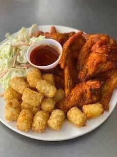 Plate of fried chicken tenders, tater tots, coleslaw, and dipping sauce on a white plate.