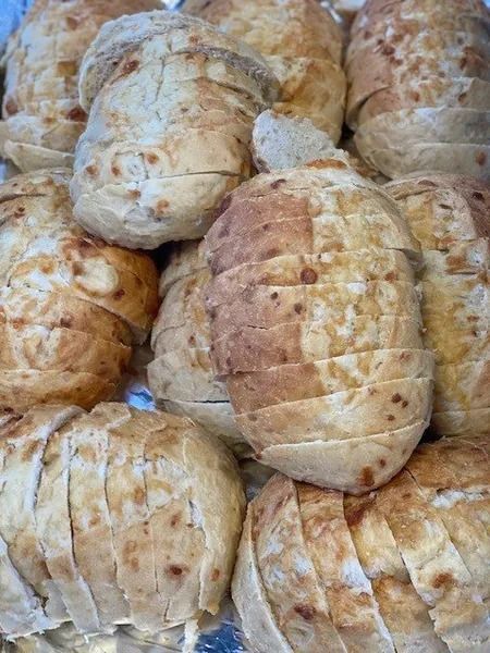 Fresh bread rolls stacked close together, golden-brown with a lightly scored crust