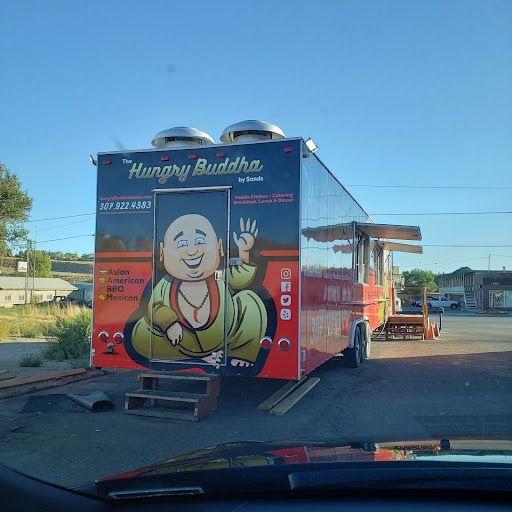 Hungry Buddha food truck with smiling Buddha graphic parked in a lot under a clear blue sky
