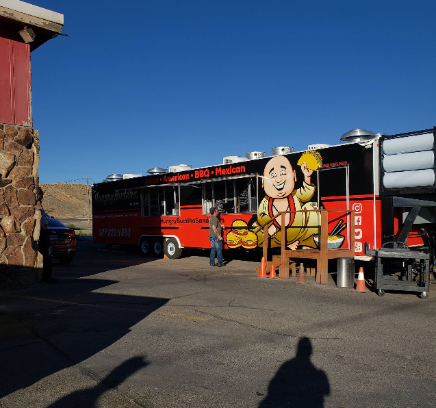 Outdoor red bus beside a cartoon statue at a sunny roadside stop