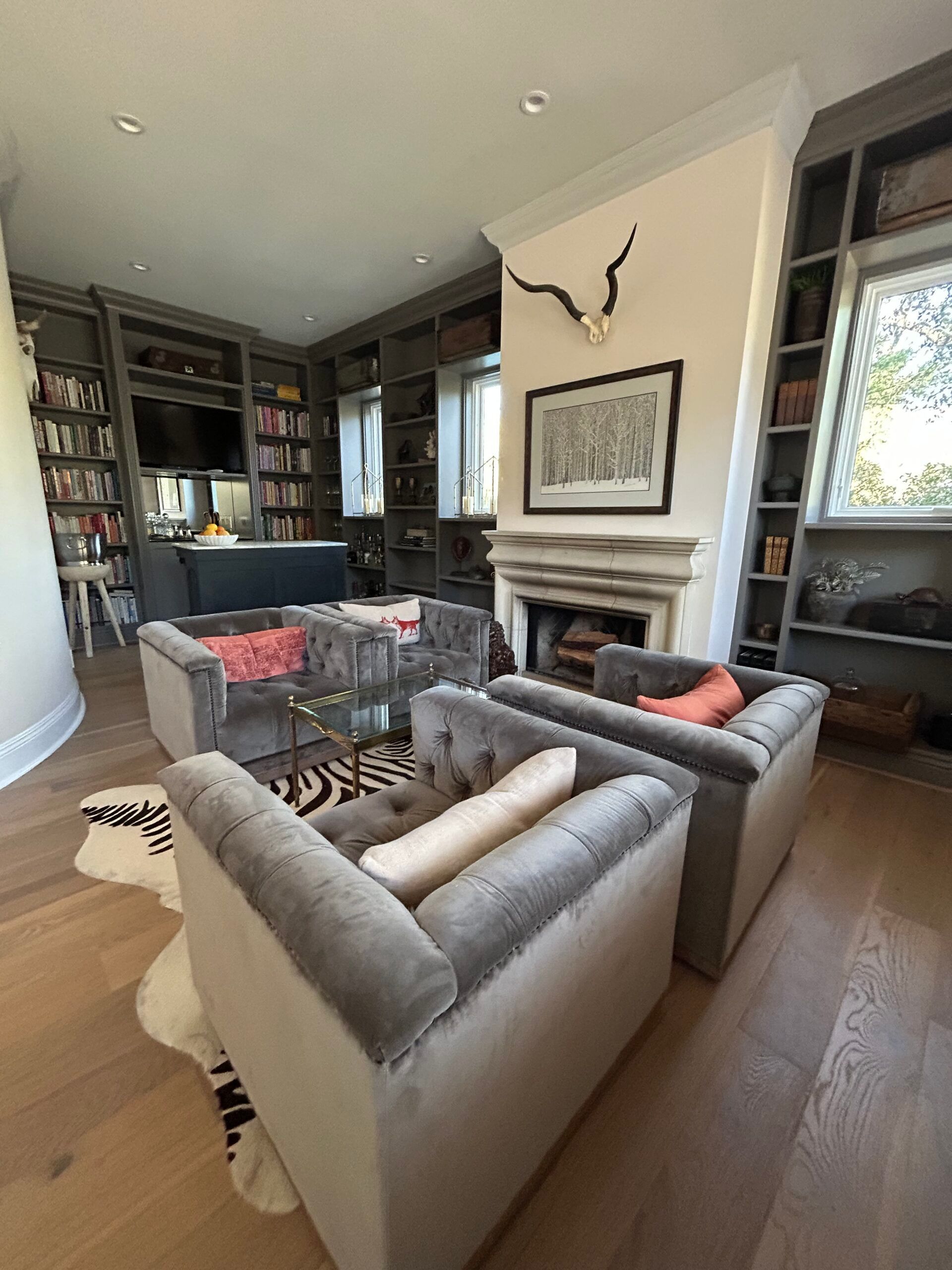 Living room with grey sofas, bookshelves, zebra rug, fireplace, and wood floors.