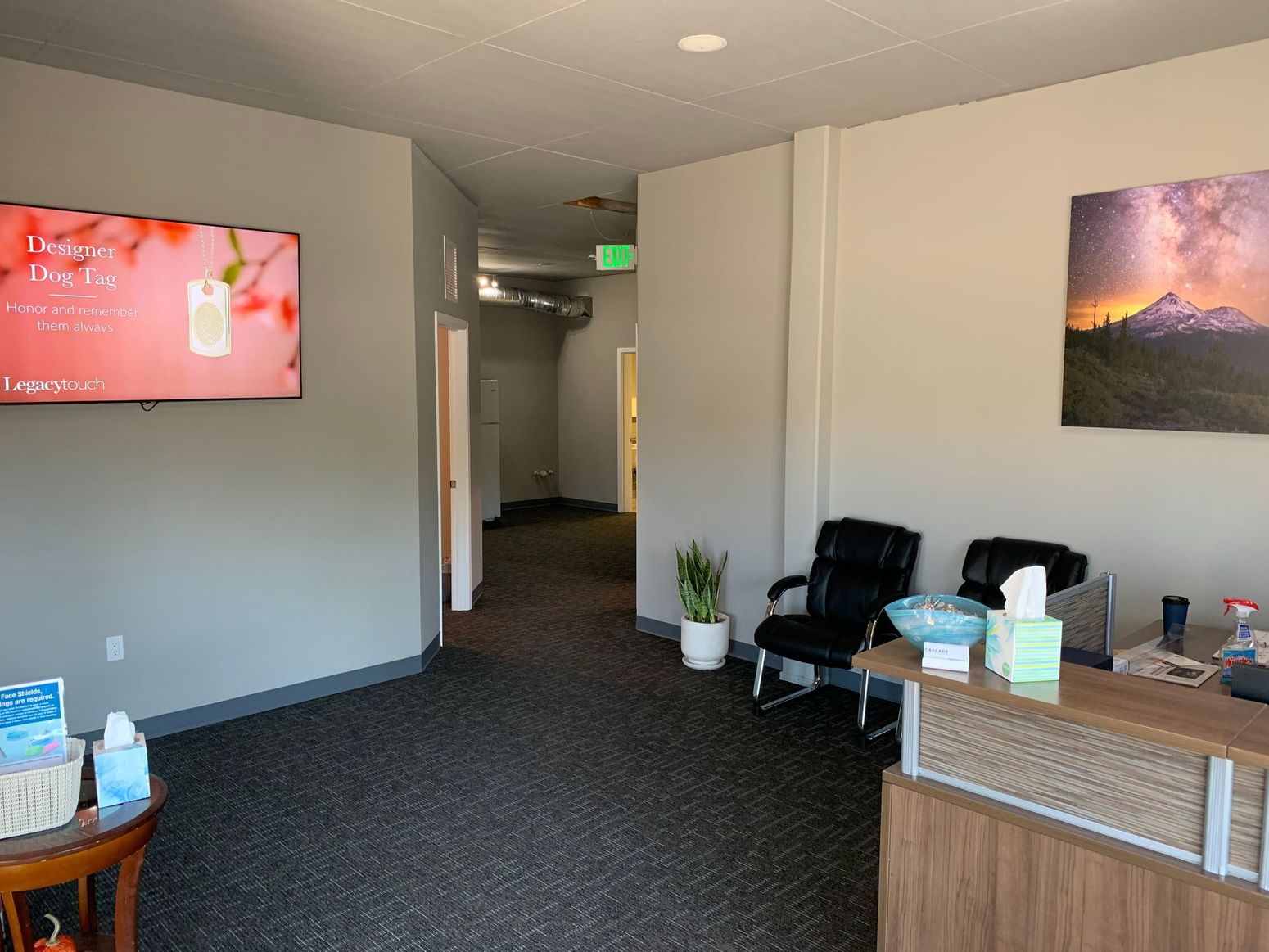 Office waiting room with chairs, a front desk, wall art, and a hallway
