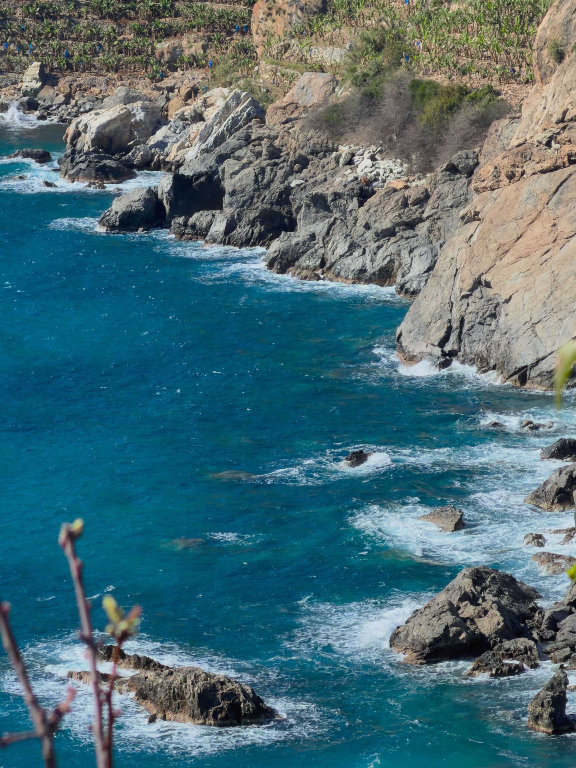 Rocky coastline with turquoise waves breaking against steep cliffs