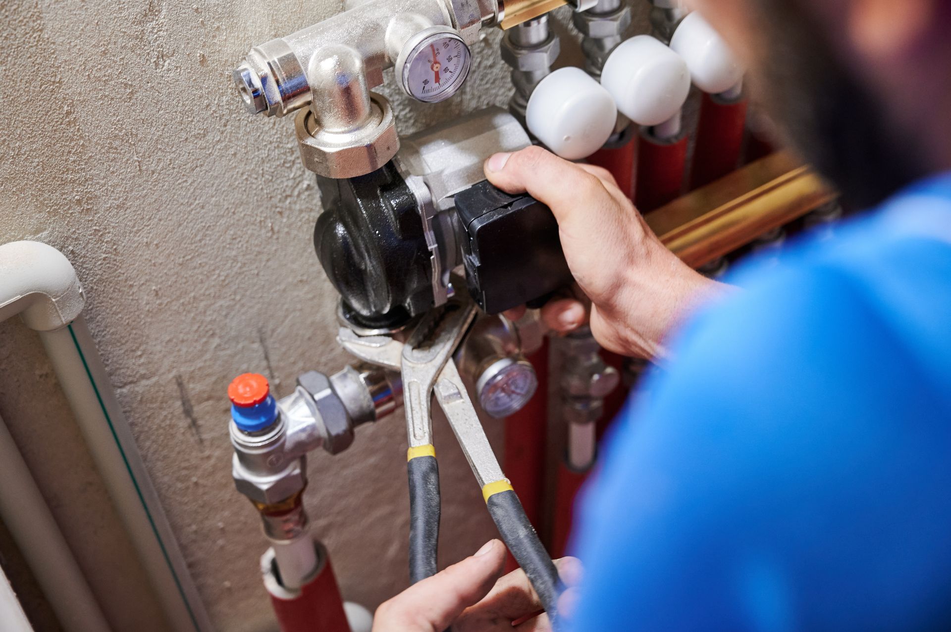 Technician adjusting a hydronic heating pump and valves on a residential plumbing system.